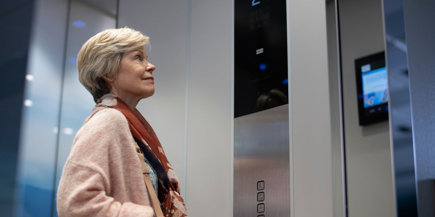 Elderly woman looking at information screen in an elevator.